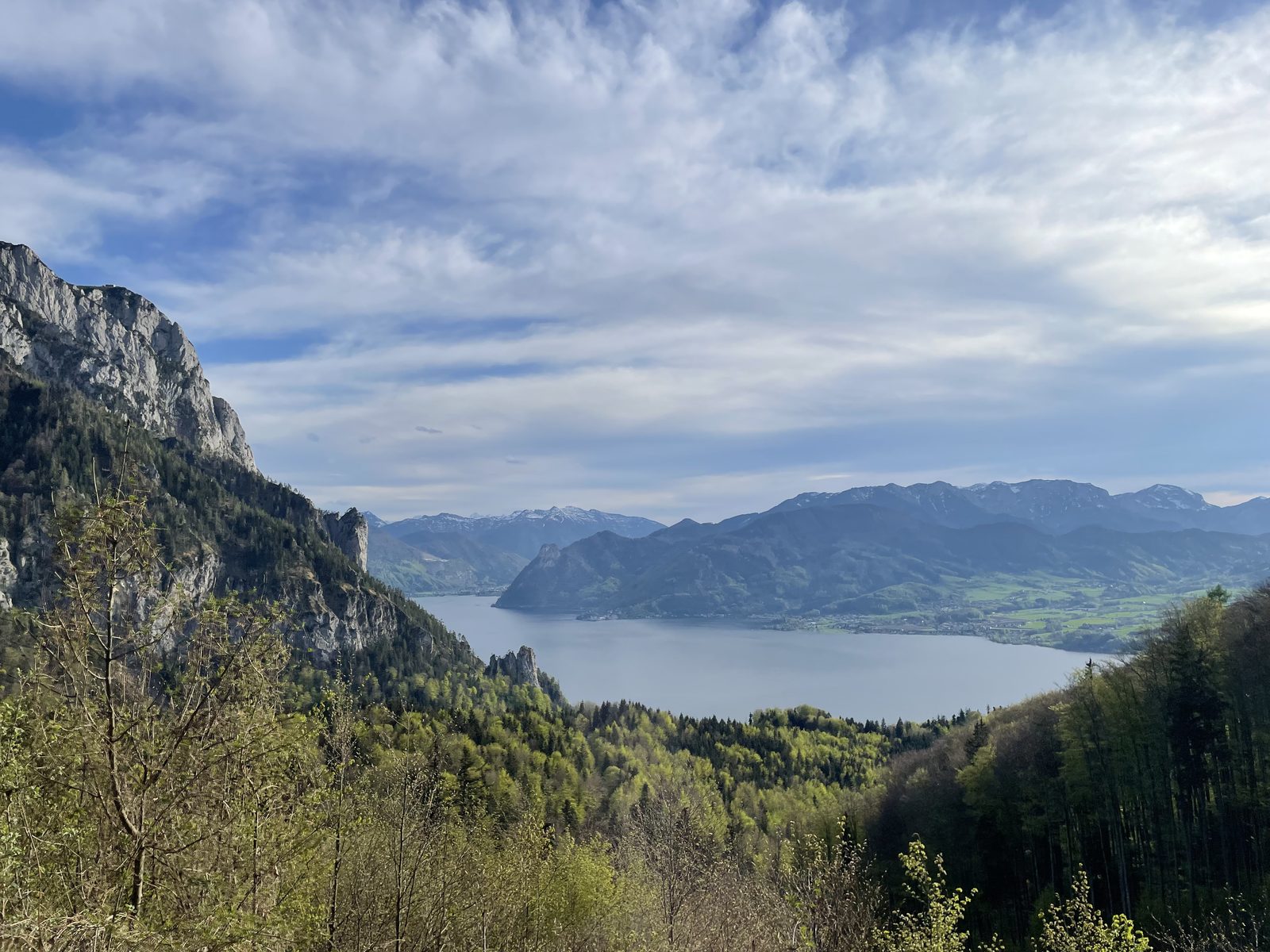 A lake surrounded by mountains, seen from a forested trail