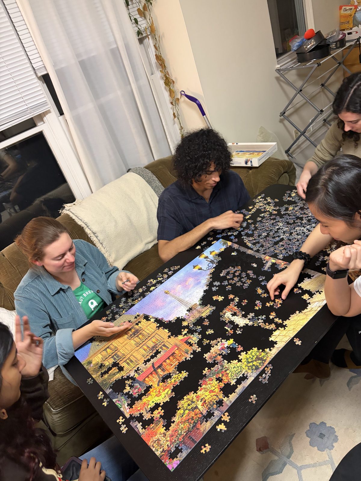 Friends gathered around a table working on a large jigsaw puzzle